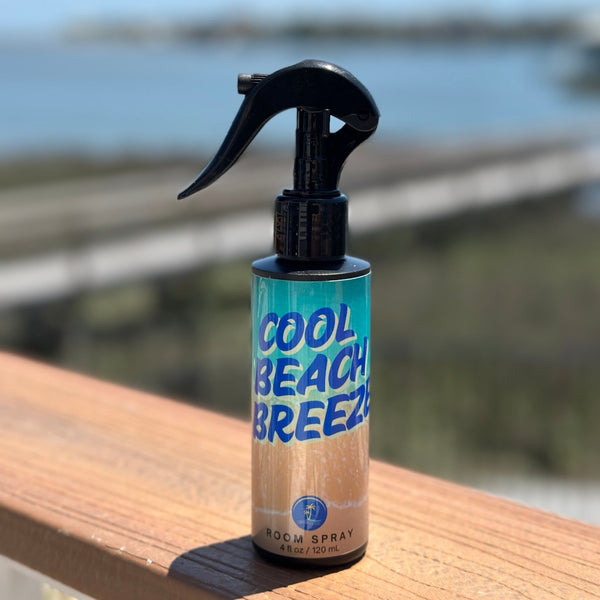 Spray bottle labeled 'Cool Beach Breeze' on a wooden surface with a blurred outdoor background