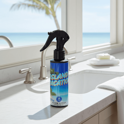 Room spray bottle labeled 'Island Vacation' on a bathroom counter with a window view of the ocean.