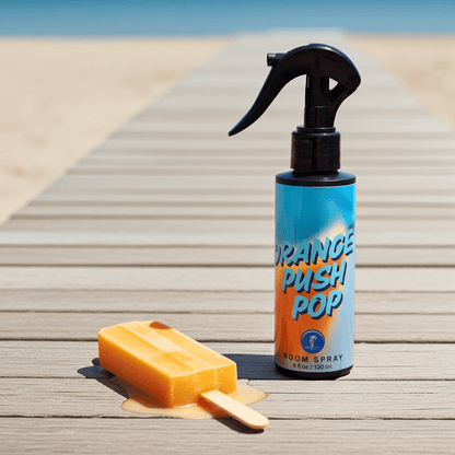 Spray bottle labeled 'Orange Push Pop' and a popsicle on a wooden surface with a beach background.