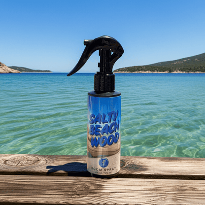Salty Beach Wood room spray bottle on a wooden ledge with a scenic ocean background