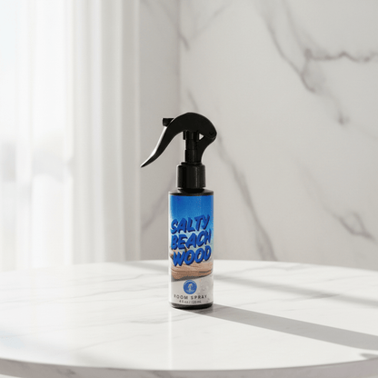 Salty Beach Wood room spray bottle on a white surface with a light gray curtain background