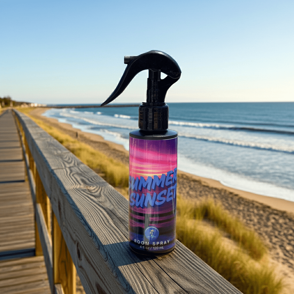 Bottle of 'Summer Sunset' room spray on a wooden railing with a beach background