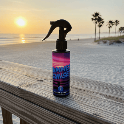 Bottle of 'Summer Sunset' room spray on a wooden surface with a beach sunset background